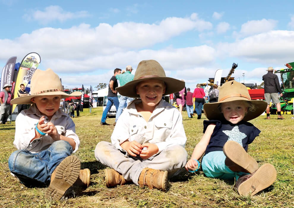 Three children sitting on grass smiling at camera