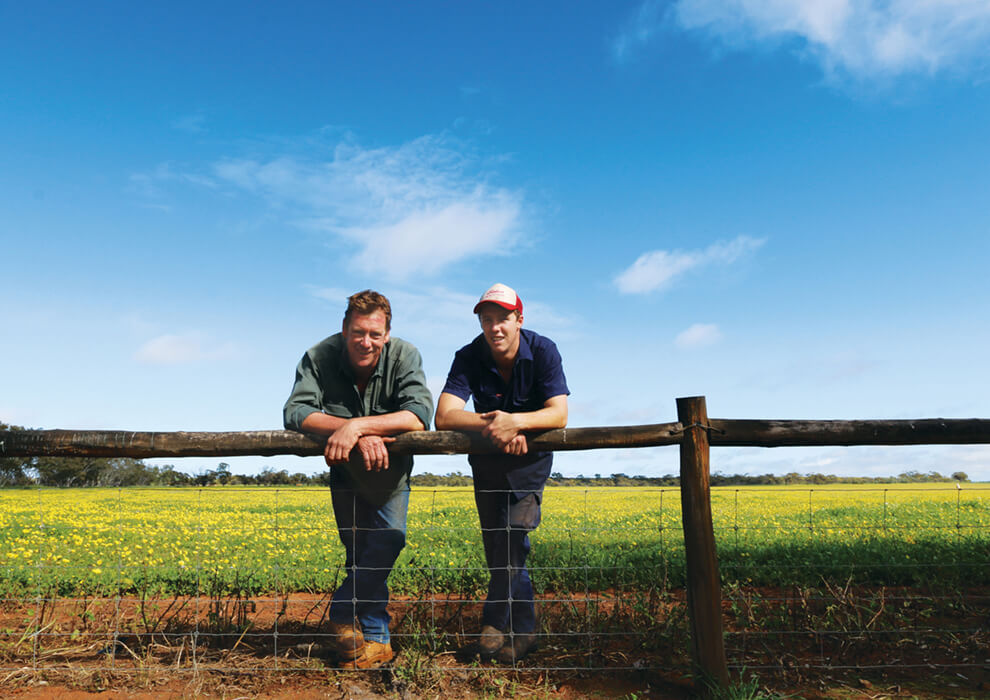 Two farmers leaning on a fence